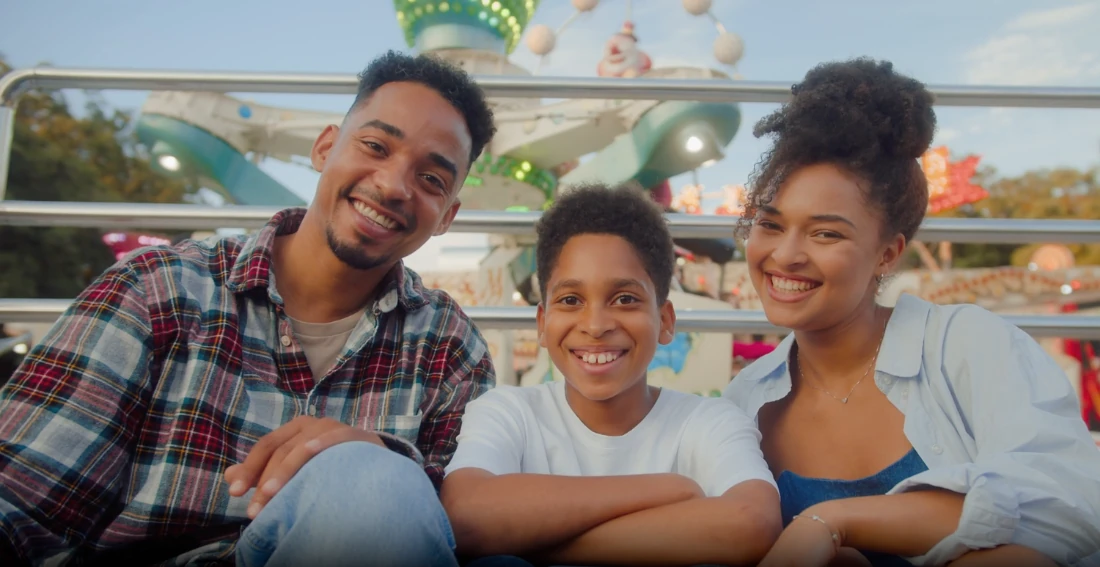A family smiling together at a fairground.