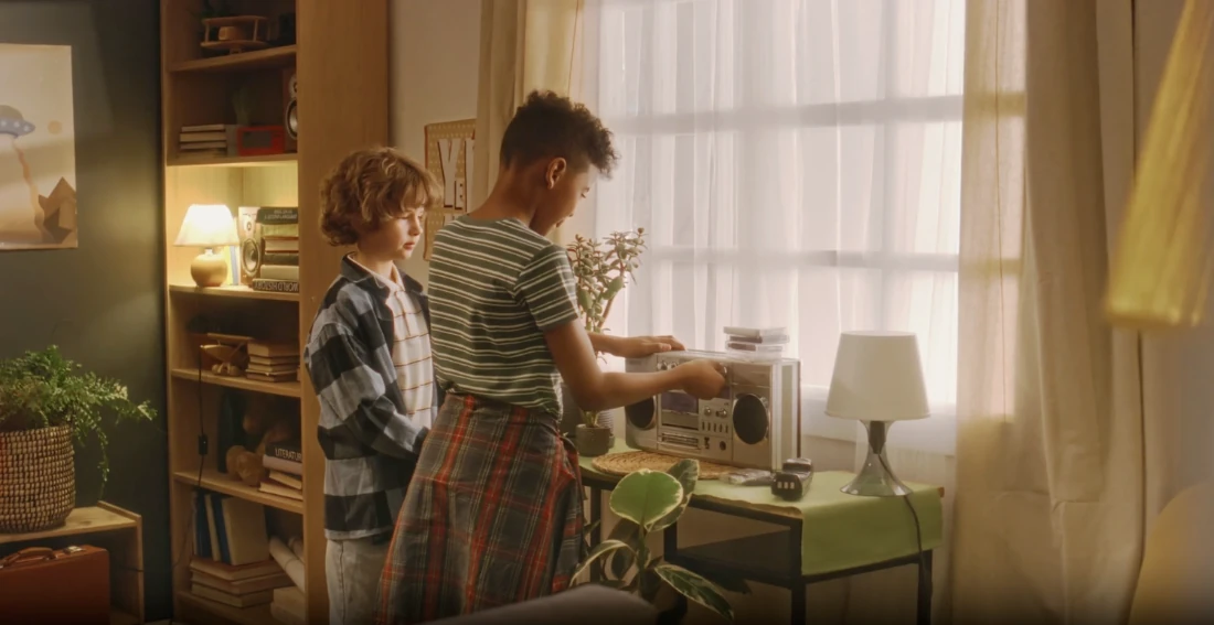 Two teenagers by a window with a stereo.