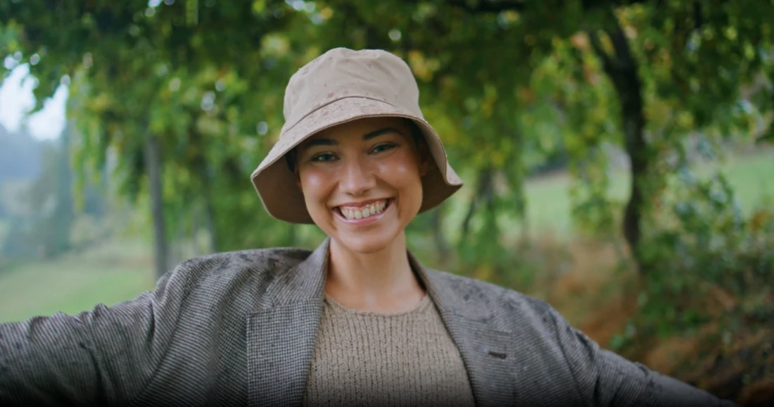 A student in a bucket hat under trees.