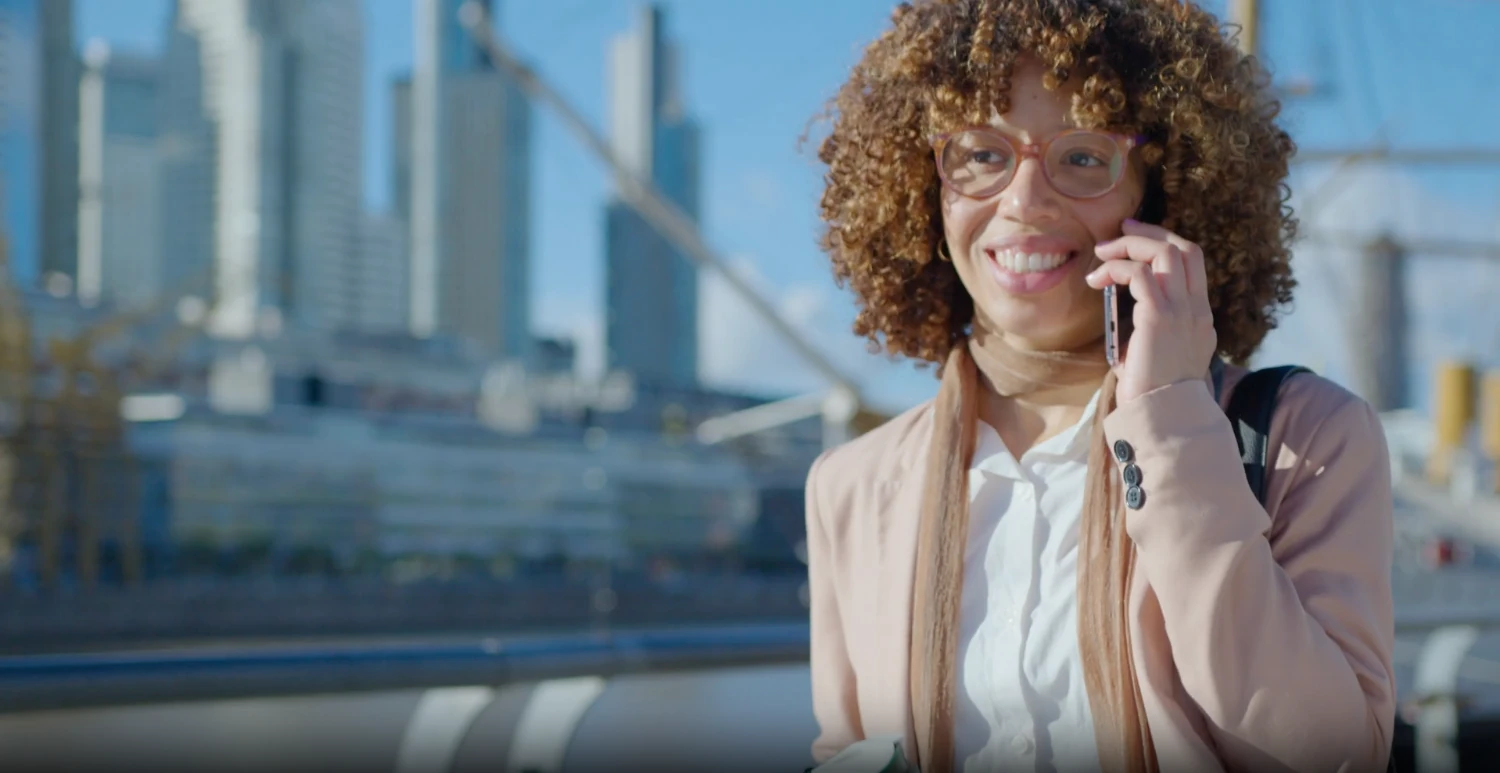 A coordinator smiling on the phone by the water.