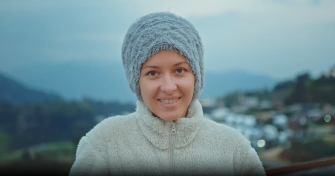 A student on a mountain path in a knitted hat.