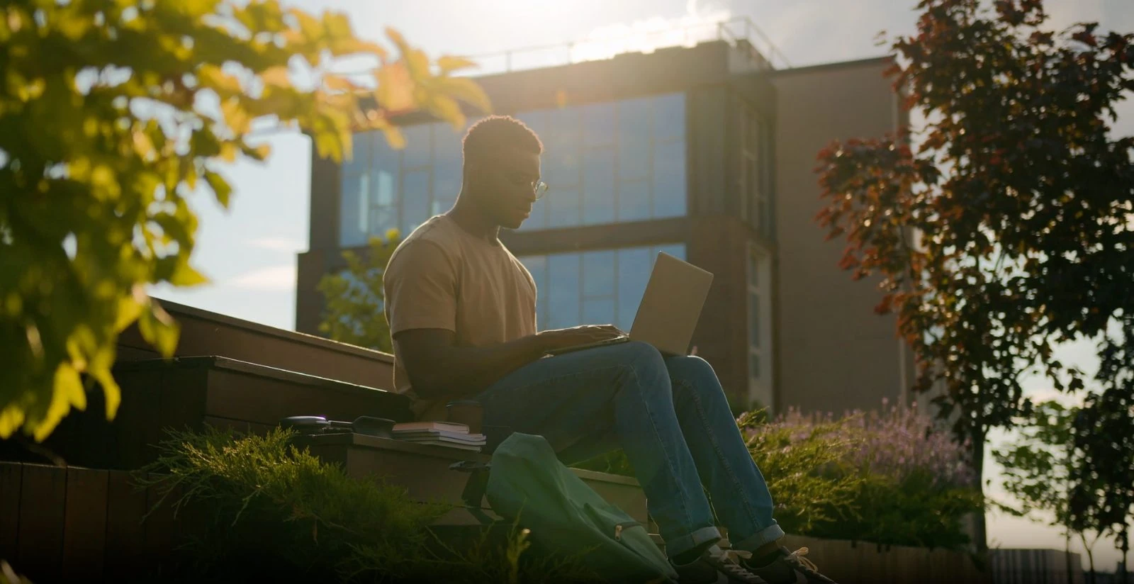 A staff member working on a laptop outside at golden hour.